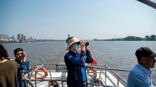 中國遊客在中朝邊境城鎮丹東的鴨綠江上觀望朝鮮邊界。