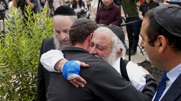 犹太教堂枪击案中，拉比古德斯坦（Ysrael Goldstein）（右二）的手中被枪手打中，在4月28日的新闻发布会后，他拥抱了会众（照片来源：SANDY HUFFAKER / AFP / Getty Images）