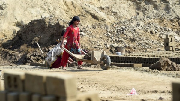 一名巴基斯坦女孩在拉合尔郊区的一个砖窑上推着一辆带沙子的车