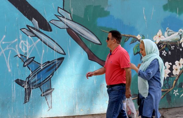 2019年6月22日，美国驻伊朗首都德黑兰大使馆外，有伊朗人在一幅战争主题的i壁画前走过。