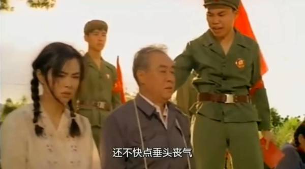 教育部長掛著批鬥牌，和女兒阿珊（王祖賢飾）一同下跪，接受「教育」。