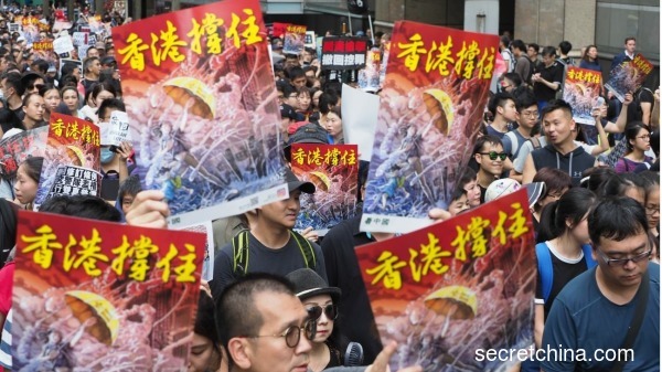 7月7日，23万香港人参加了九龙“反送中”游行，香港市民手持《看中国》印刷的“香港撑住”画报。