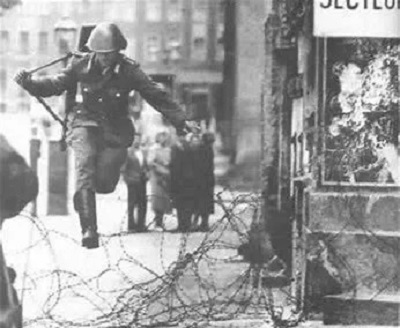 19岁青年舒曼执勤时突然甩掉步枪大步越过铁丝网，成为东德第一位穿越围墙，投奔自由的东柏林人。